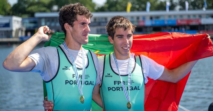 Pedro Rodrigues e Tomás Neves celebram o título no Mundial de Remo Sub-23 Pedro Rodrigues e Tomás Neves exibem as medalhas de ouro e a bandeira de Portugal após a vitória no Mundial de Remo Sub-23, em Duisburgo