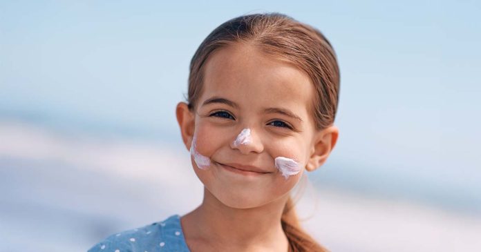 Proteção solar infantil aplicada no rosto de uma criança durante um dia de verão para proteger a pele dos raios UV.
