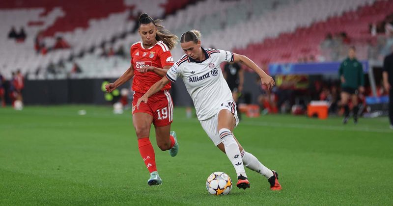 Jogadora do Bayern Munique conduz a bola sob press&atilde;o da jogadora n&uacute;mero 19 do Benfica durante o Benfica-Bayern na Luz