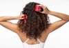 Cabelo danificado pelo verão é o foco da rotina de quatro passos da Wella Professionals Mulher de costas com cabelo encaracolado segura produtos Wella Ultimate Repair para o cuidado do cabelo danificado pelo verão