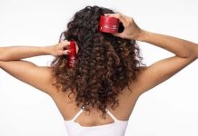 Cabelo danificado pelo verão é o foco da rotina de quatro passos da Wella Professionals Mulher de costas com cabelo encaracolado segura produtos Wella Ultimate Repair para o cuidado do cabelo danificado pelo verão