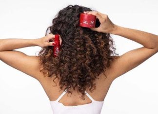 Cabelo danificado pelo verão é o foco da rotina de quatro passos da Wella Professionals Mulher de costas com cabelo encaracolado segura produtos Wella Ultimate Repair para o cuidado do cabelo danificado pelo verão