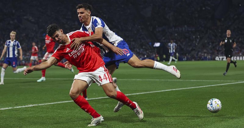 Jogador do Benfica com a bola controlado sob press&atilde;o de atleta do FC Porto no cl&aacute;ssico no Drag&atilde;o.