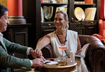 MYTHIC SANA, o hotel de Lisboa que revela ‘The privilege of stillness num novo filme promocional Joaquim de Almeida e uma mulher sentados à mesa numa cena do filme promocional do MYTHIC SANA
