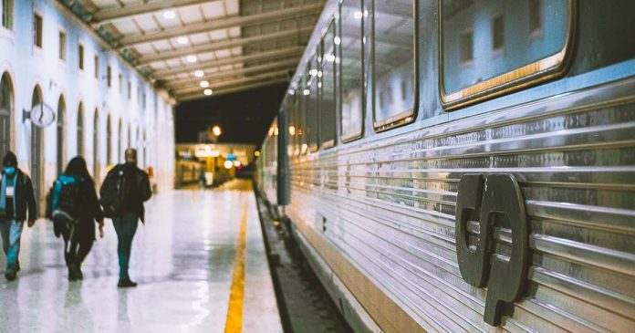Comboio parado numa estação com passageiros na plataforma, numa imagem associada ao Passe Ferroviário Verde