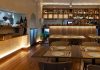 Restaurante Vizinhos do Rei cruza sabores e memória no coração de Odivelas Interior da sala de refeições do restaurante Vizinhos do Rei em Odivelas com mesas dispostas e balcão iluminado ao fundo