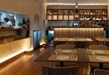 Restaurante Vizinhos do Rei cruza sabores e memória no coração de Odivelas Interior da sala de refeições do restaurante Vizinhos do Rei em Odivelas com mesas dispostas e balcão iluminado ao fundo