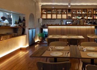 Restaurante Vizinhos do Rei cruza sabores e memória no coração de Odivelas Interior da sala de refeições do restaurante Vizinhos do Rei em Odivelas com mesas dispostas e balcão iluminado ao fundo