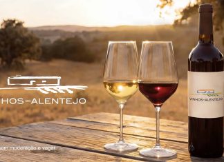 Vinhos alentejanos ligam compras a experiências no Alentejo Vinhos alentejanos com garrafa e copos de vinho numa paisagem do Alentejo