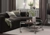 Decoração de outono da JYSK conjuga o brilho dos cromados com o conforto dos tons castanhos Sala com sofá escuro, mesa de centro em vidro e cromado com rodas e suporte de televisão na decoração de outono da JYSK