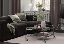 Decoração de outono da JYSK conjuga o brilho dos cromados com o conforto dos tons castanhos Sala com sofá escuro, mesa de centro em vidro e cromado com rodas e suporte de televisão na decoração de outono da JYSK