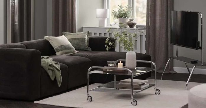Decoração de outono da JYSK na sala de estar Sala com sofá escuro, mesa de centro em vidro e cromado com rodas e suporte de televisão na decoração de outono da JYSK