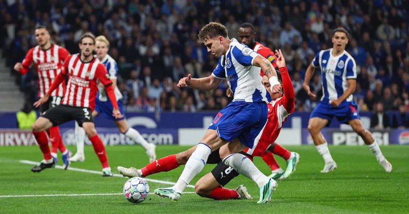 Jogador portista disputa a bola com um advers&aacute;rio que tenta um corte em deslize, no encontro entre FC Porto e PSV