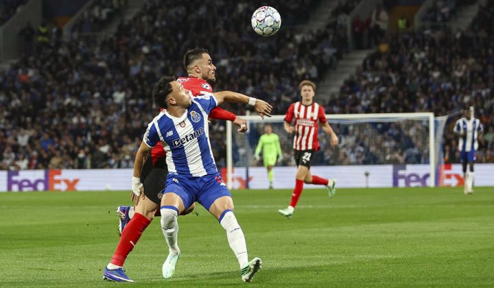 Jogadores do FC Porto e PSV disputam posi&ccedil;&atilde;o enquanto acompanham uma bola pelo ar, no Est&aacute;dio do Drag&atilde;o