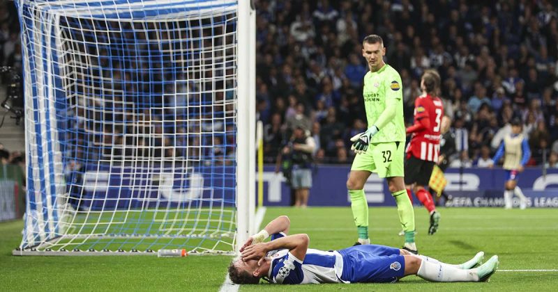 Jogador portista deitado no relvado, com as m&atilde;os no rosto, junto &agrave; baliza do PSV, durante o encontro entre FC Porto e PSV