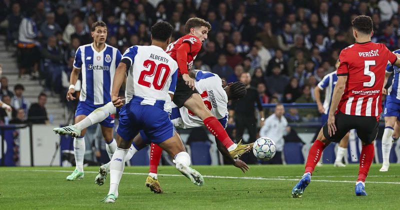 Jogadores do FC Porto e PSV disputam a bola, com um jogador portista em desequil&iacute;brio entre advers&aacute;rios