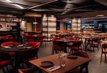 Grelhados no 550º ganham novos contrastes na cozinha de David Casaca Sala com mesas de madeira, cadeiras em tons quentes e bar ao fundo, onde são servidos os grelhados no 550º, em Lisboa