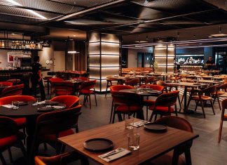 Grelhados no 550º ganham novos contrastes na cozinha de David Casaca Sala com mesas de madeira, cadeiras em tons quentes e bar ao fundo, onde são servidos os grelhados no 550º, em Lisboa