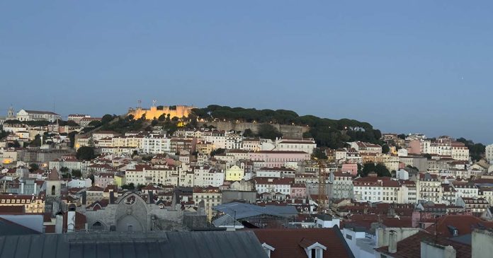 Vista de Lisboa ao anoitecer, com o Castelo de São Jorge iluminado, a ilustrar a notícia sobre os prémios de turismo atribuídos a Portugal.