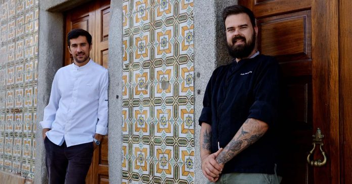 João Narigueta e Miguel Dominguinhos — Restaurante HÍBRIDO João Narigueta e Miguel Dominguinhos, responsáveis pelo restaurante HÍBRIDO, junto a portas de madeira e uma fachada revestida a azulejos