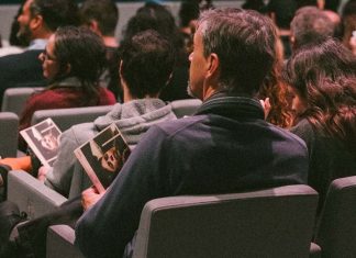 Teatro em Lisboa ganha acompanhamento gratuito para quem não consegue ir sozinho Teatro em Lisboa: espectadores sentados numa sala de espetáculos, alguns com programas nas mãos