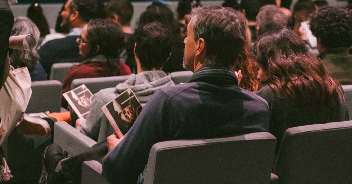 Teatro em Lisboa: espectadores sentados numa sala de espetáculos, alguns com programas nas mãos
