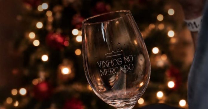 Copo Vinhos no Mercado com decoração natalícia ao fundo, no ambiente do evento.